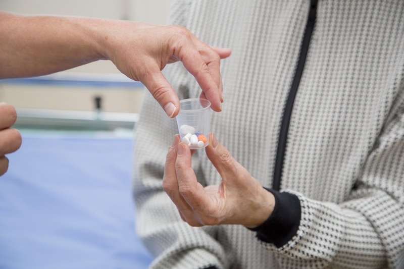 Terveydenhuollon työntekijä antaa potilaalle lääkkeet pienessä muovikupissa.